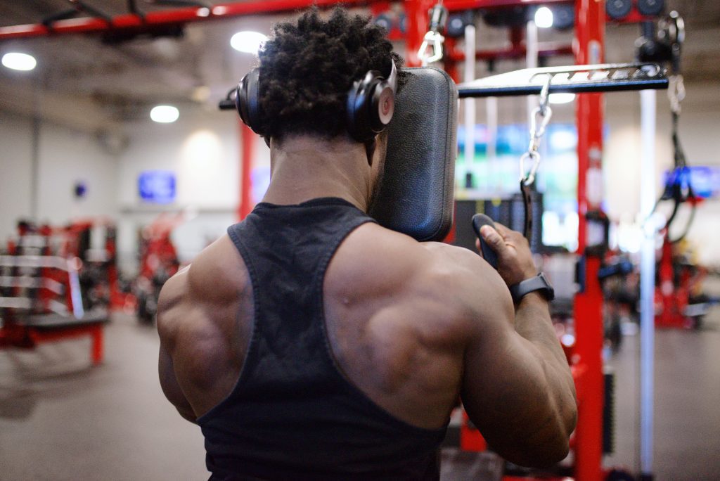 back of black man performing chest supported lat pulldown