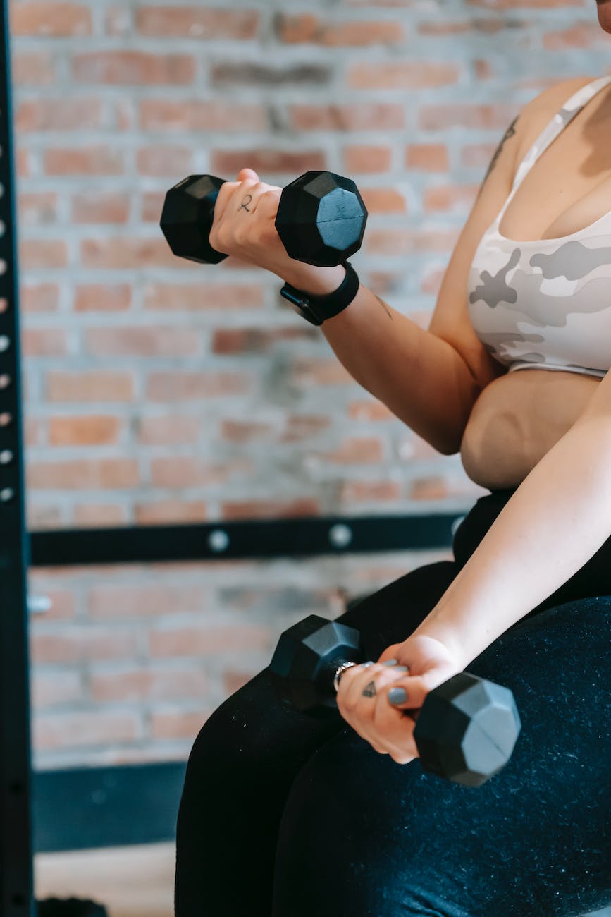 overweight woman lifting dumbbells during intense workout in gym to lose body fat