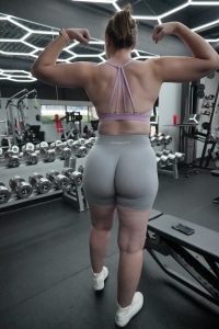 Female client proudly posing to show her defined back muscles after completing the glute workshop at Fitness Factory KC.