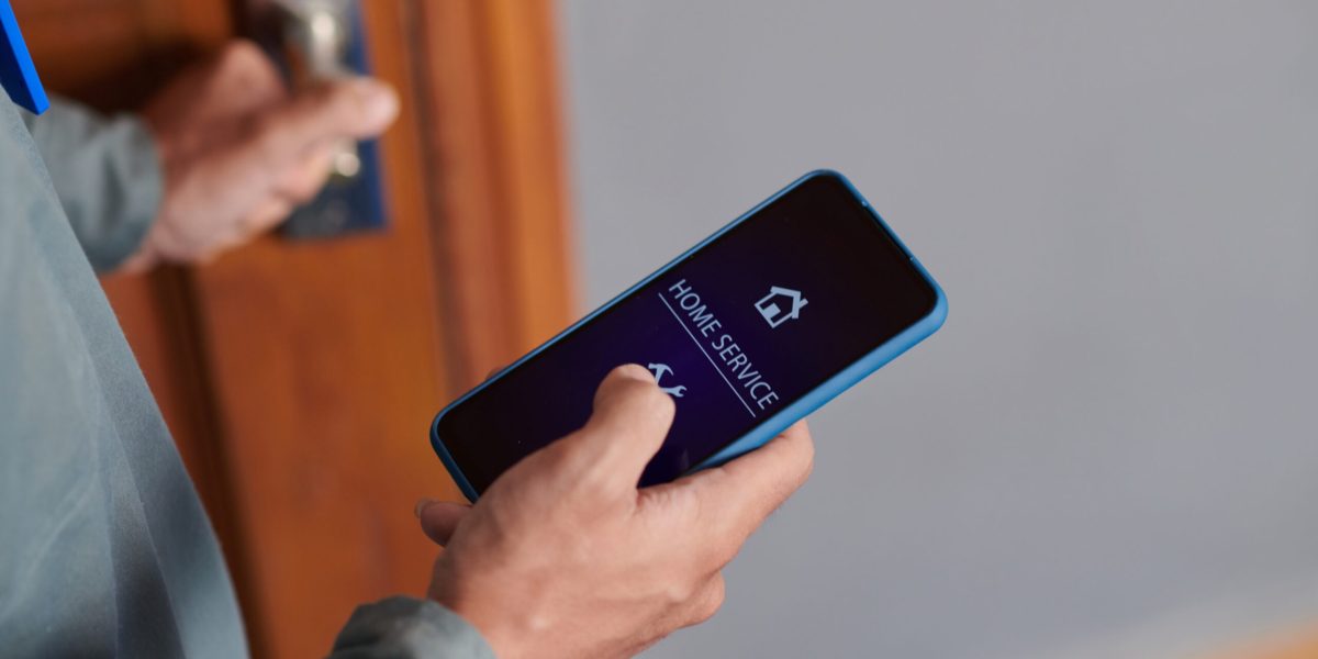 Hands of home service worker holding smartphone with mobile application